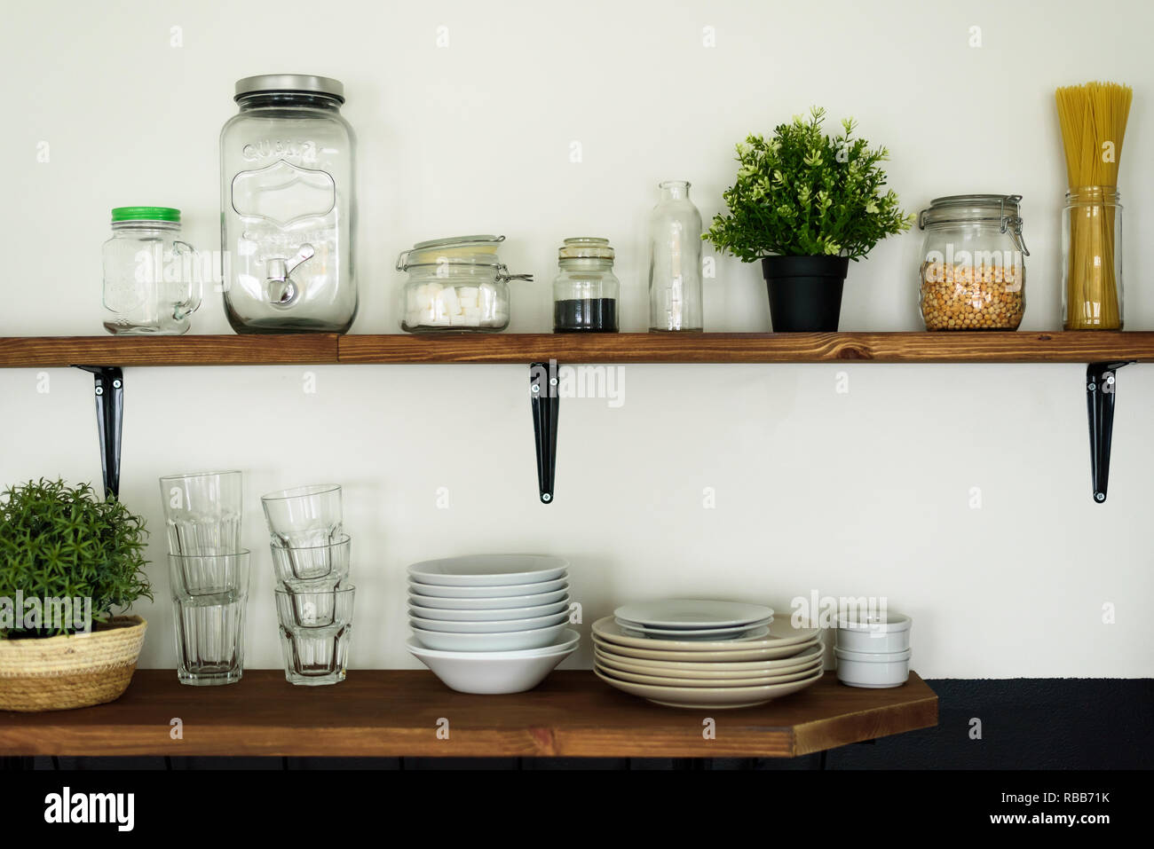 Dish and decorations on open wooden shelves in white kitchen Stock