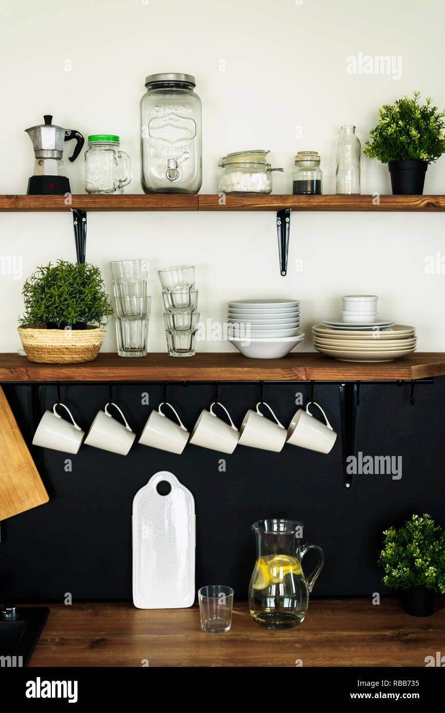 Dish and decorations on open wooden shelves in white kitchen Stock