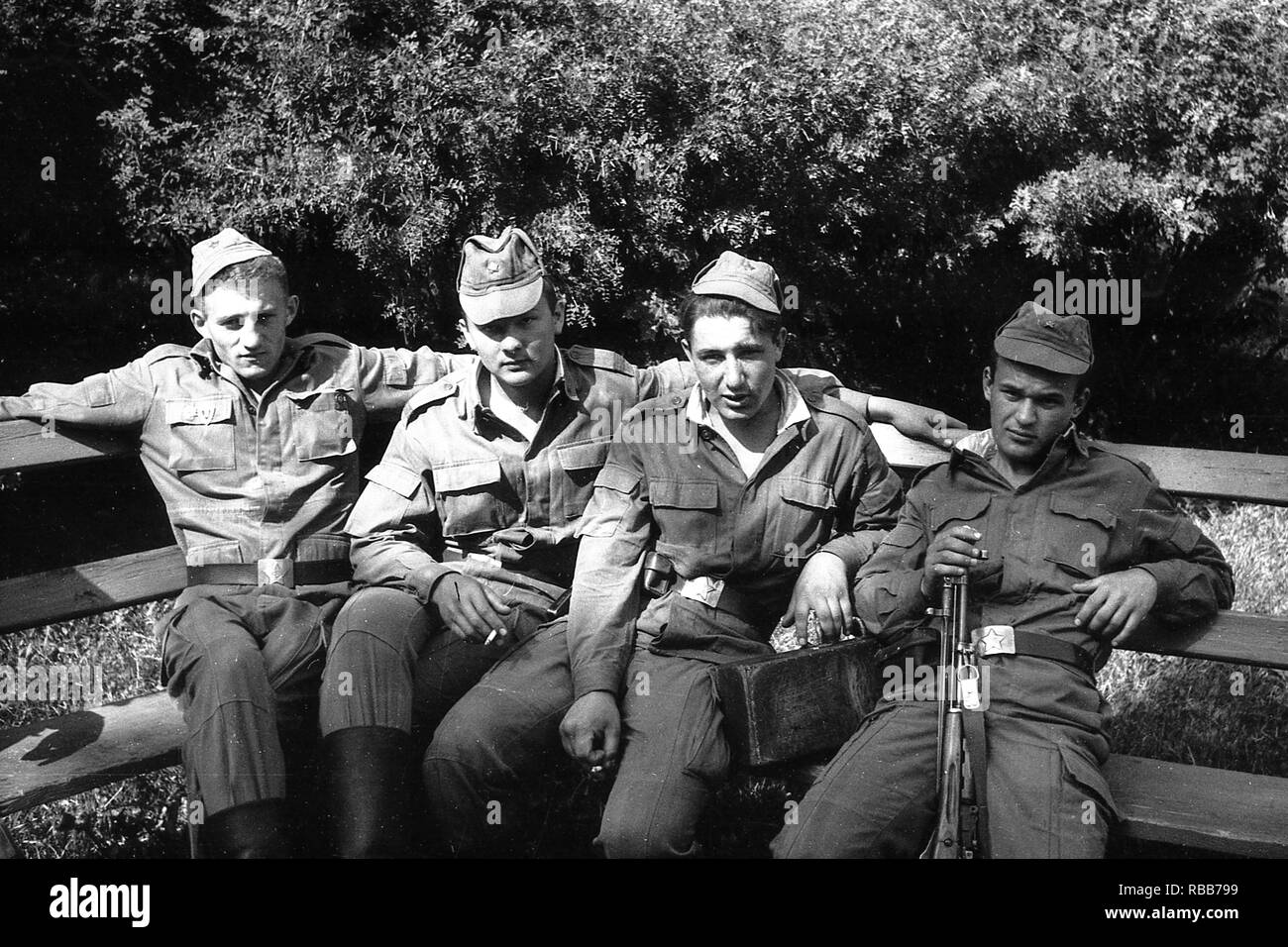 MOSCOW REGION, RUSSIA - CIRCA 1992: Soldiers of the Russian army are sitting on a wooden bench. Film scan. Large grain. Stock Photo