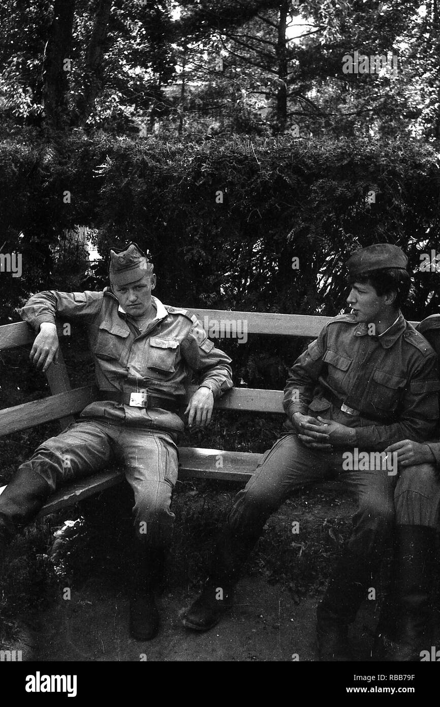 MOSCOW REGION, RUSSIA - CIRCA 1992: Soldiers of the Russian army are sitting on a wooden bench. Film scan. Large grain. Stock Photo