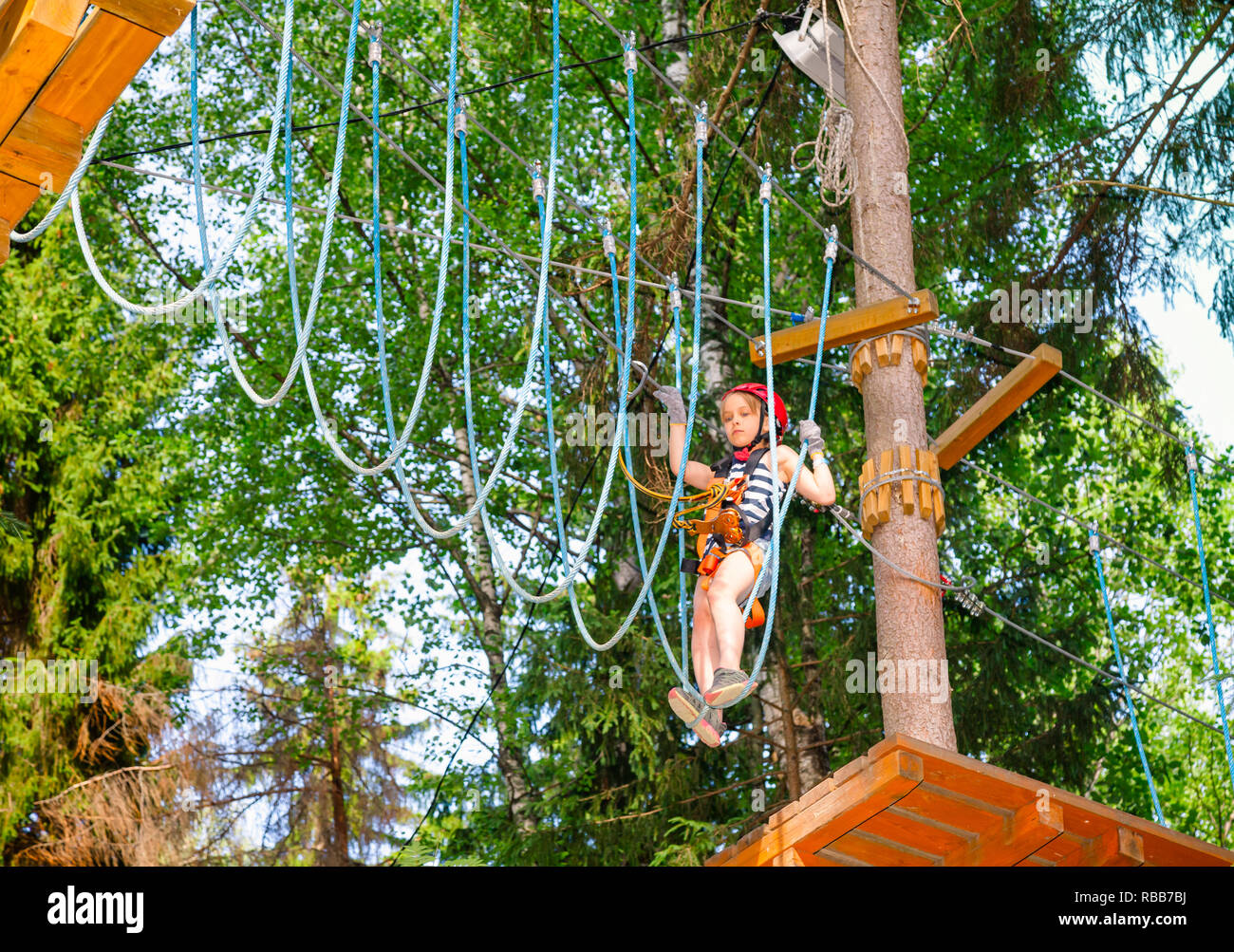 Brave elementary age girl wearing safety harness climbing at a ropes