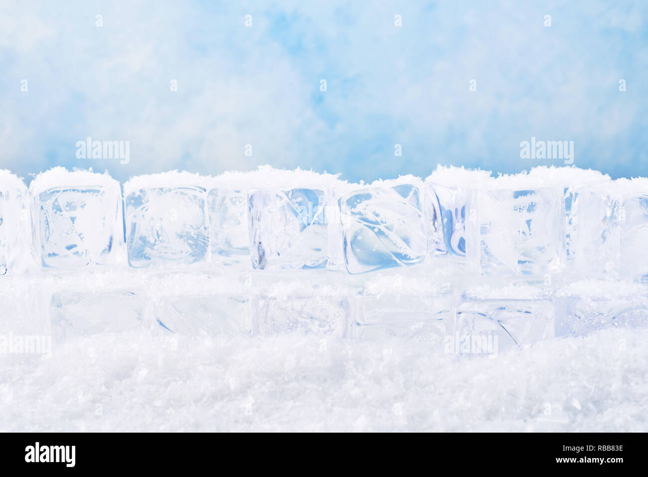 Ice cubes with snow over blue background. Copy space for text or design element. Stock Photo