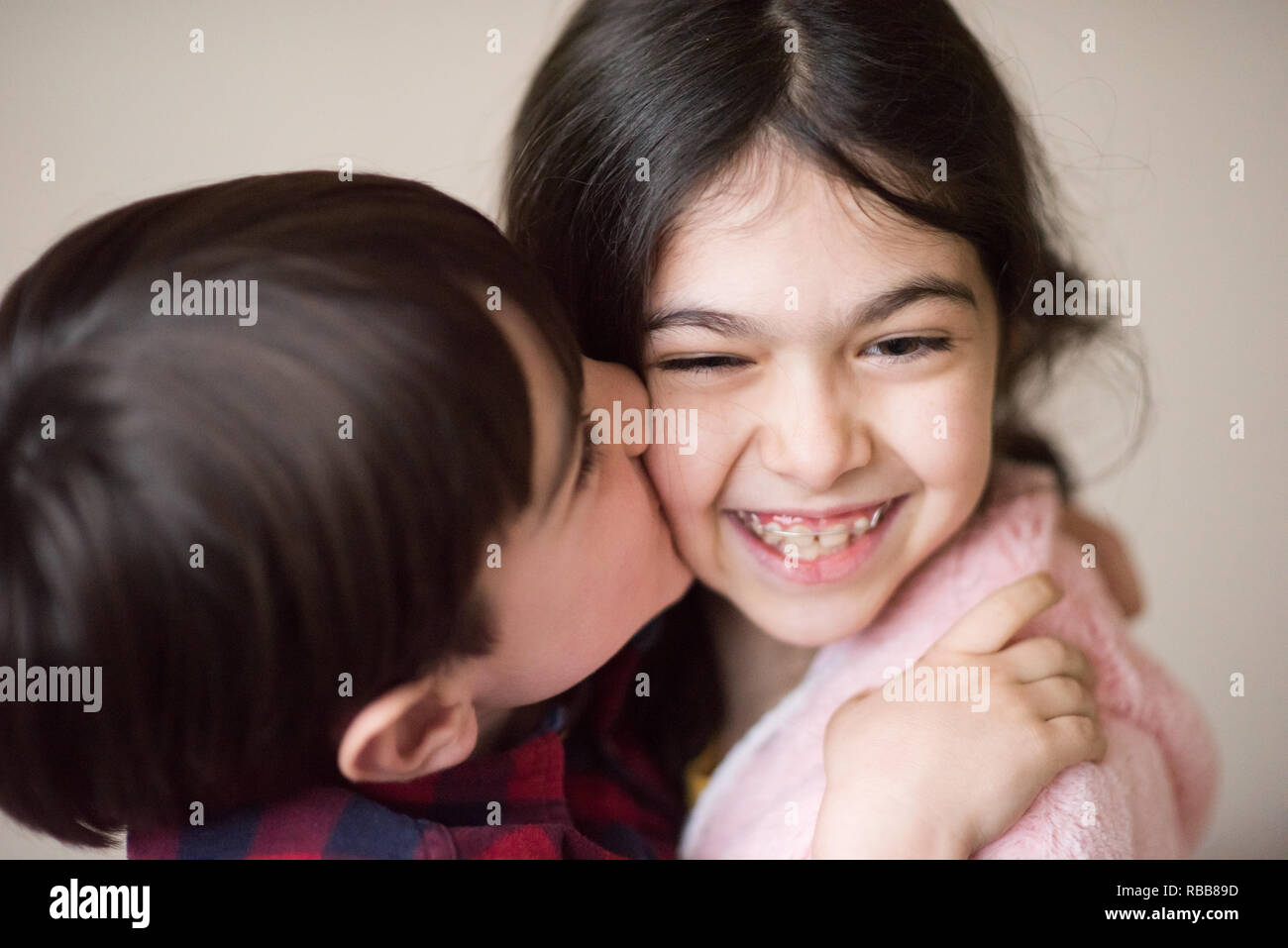 cute little caucasian boy kissing happy laughing small girl with bracket Stock Photo