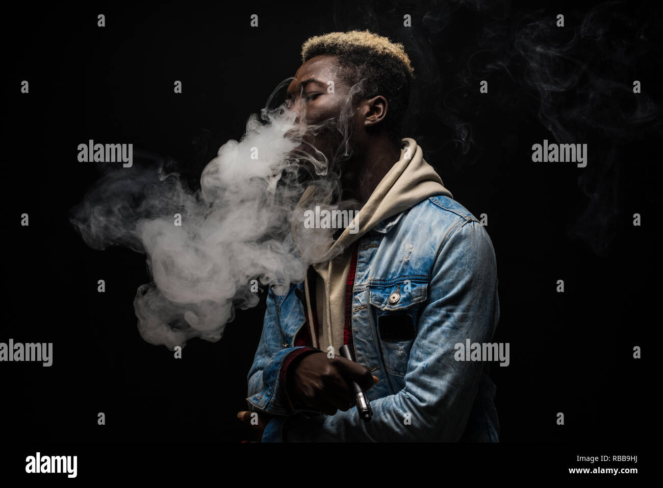 African Man vaping an electronic cigarette isolated on black Stock Photo -  Alamy