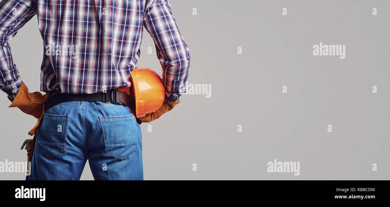 Builder man in plaid shirt and gloves wearing and holding helmet Stock Photo