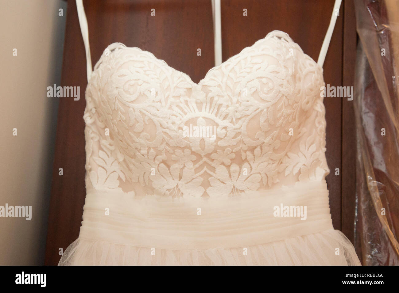 close up of a white wedding dress hanging up ready to be worn on a wedding day Stock Photo