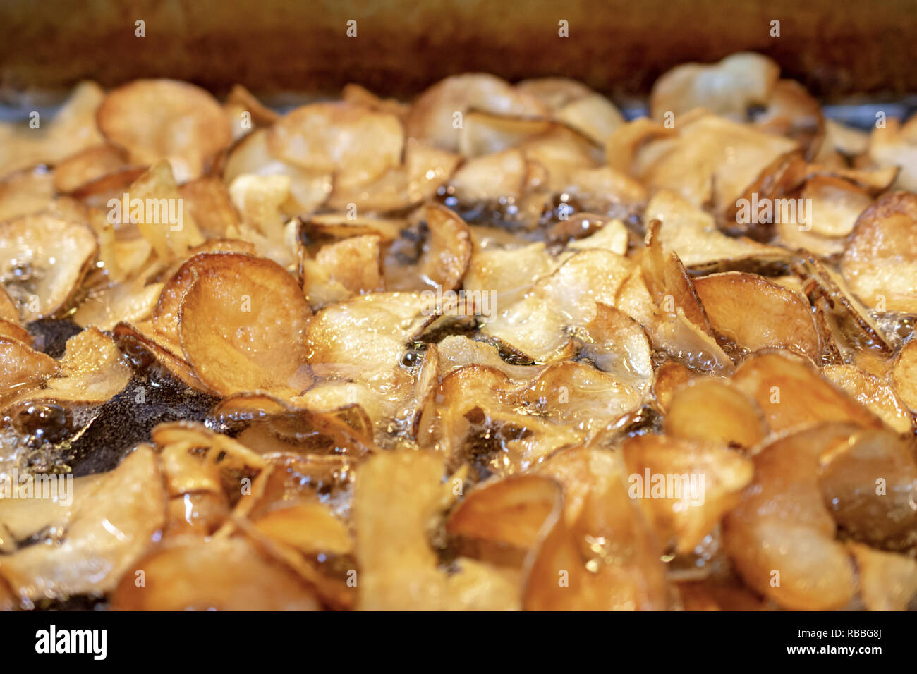 Potato chips in deep fat fryer. Macro close up with lots of bubbling