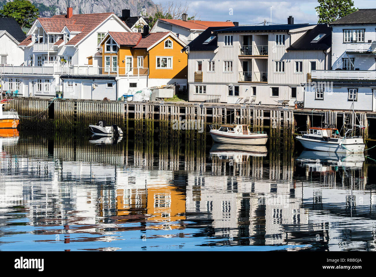 Pier at harbor in Henningsvaer, reflections of wooden houses in the calm water, Austvagöy, Lofoten, Norway Stock Photo