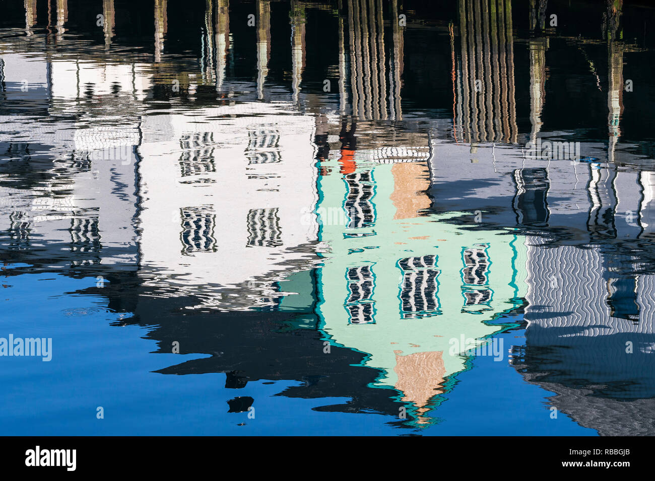 Pier at harbor in Henningsvaer, reflections of wooden houses in the calm water, Austvagöy, Lofoten, Norway Stock Photo