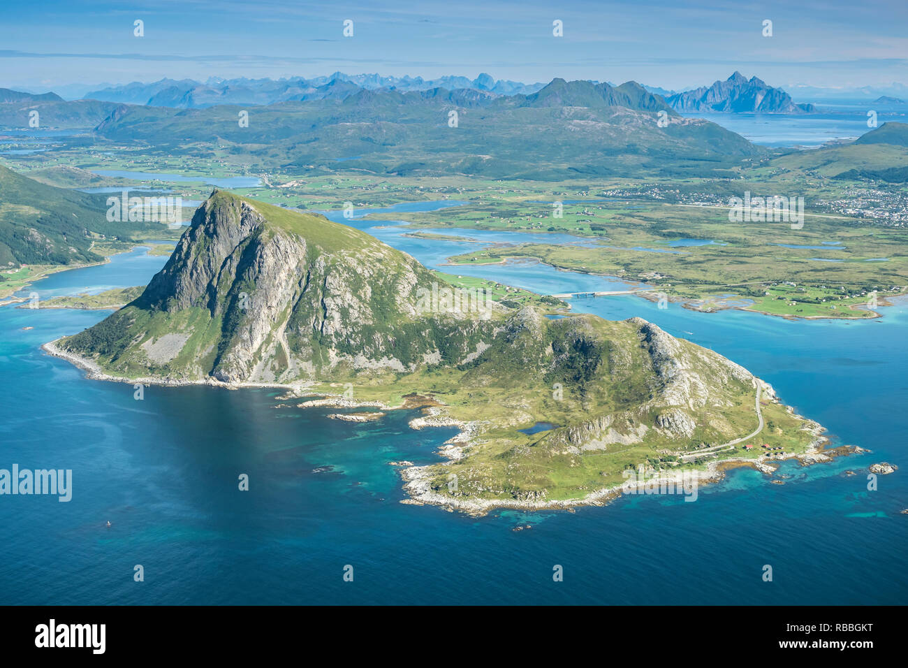 View from top of mountain Stornappstind to island Offersöya, large rock in the  sea,  mountain Vagekallen in the back, Lofoten, Norway Stock Photo