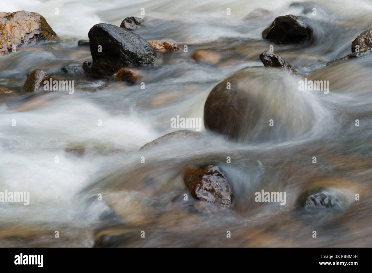close up of fast flowig river showing rocks with slow shutter showing water motion blur west gawler river tasmania Stock Photo