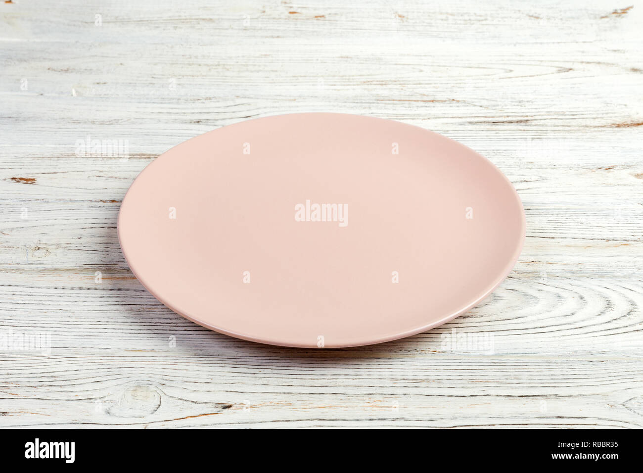 Perspective view. Empty pink matte plate on white wooden background ...