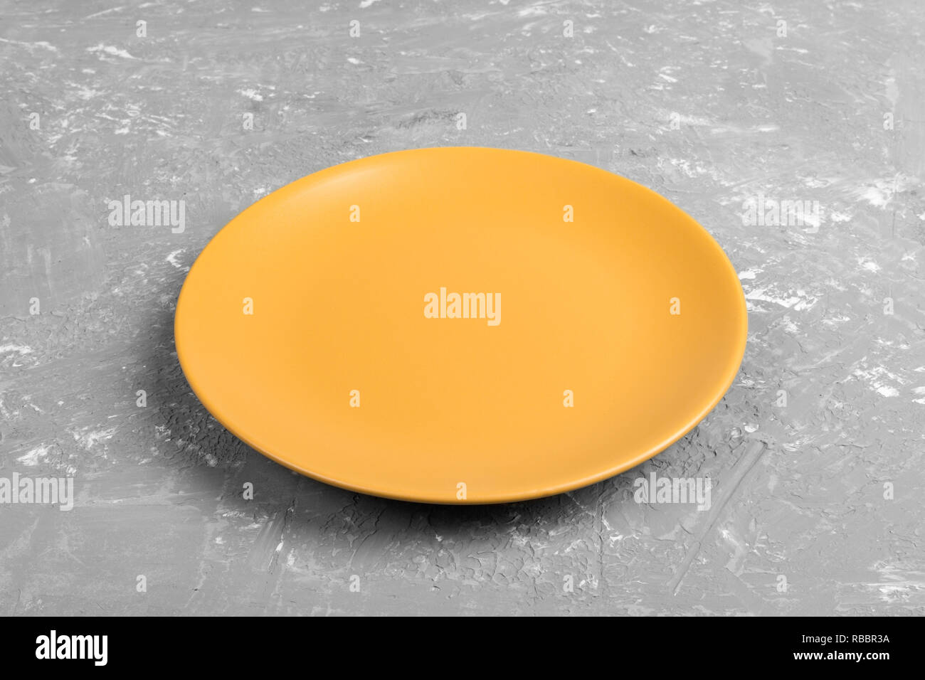 Top view of matte round empty yellow plate on grey cement background ...
