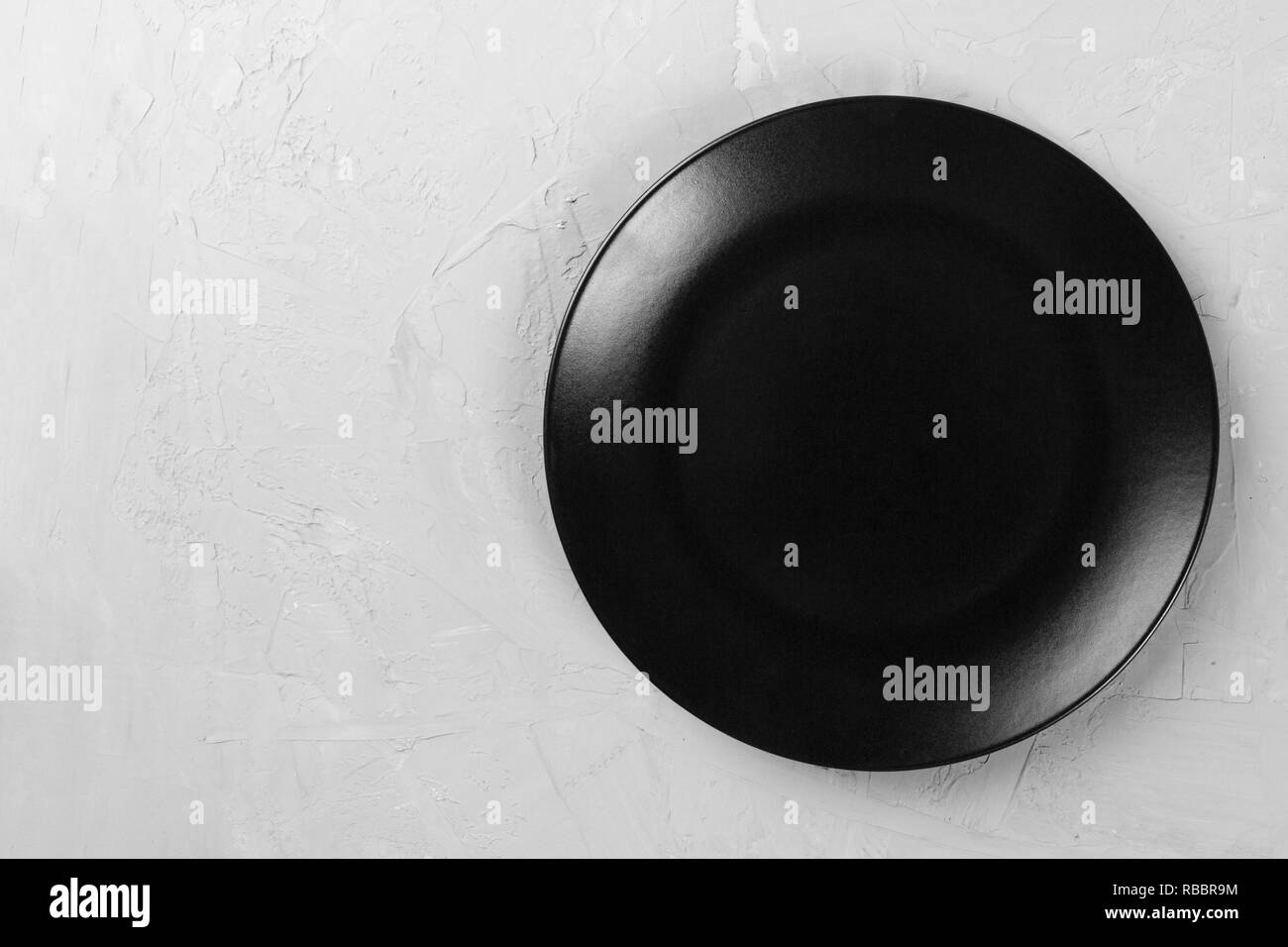 Top view of matte round empty black plate on grey cement background ...