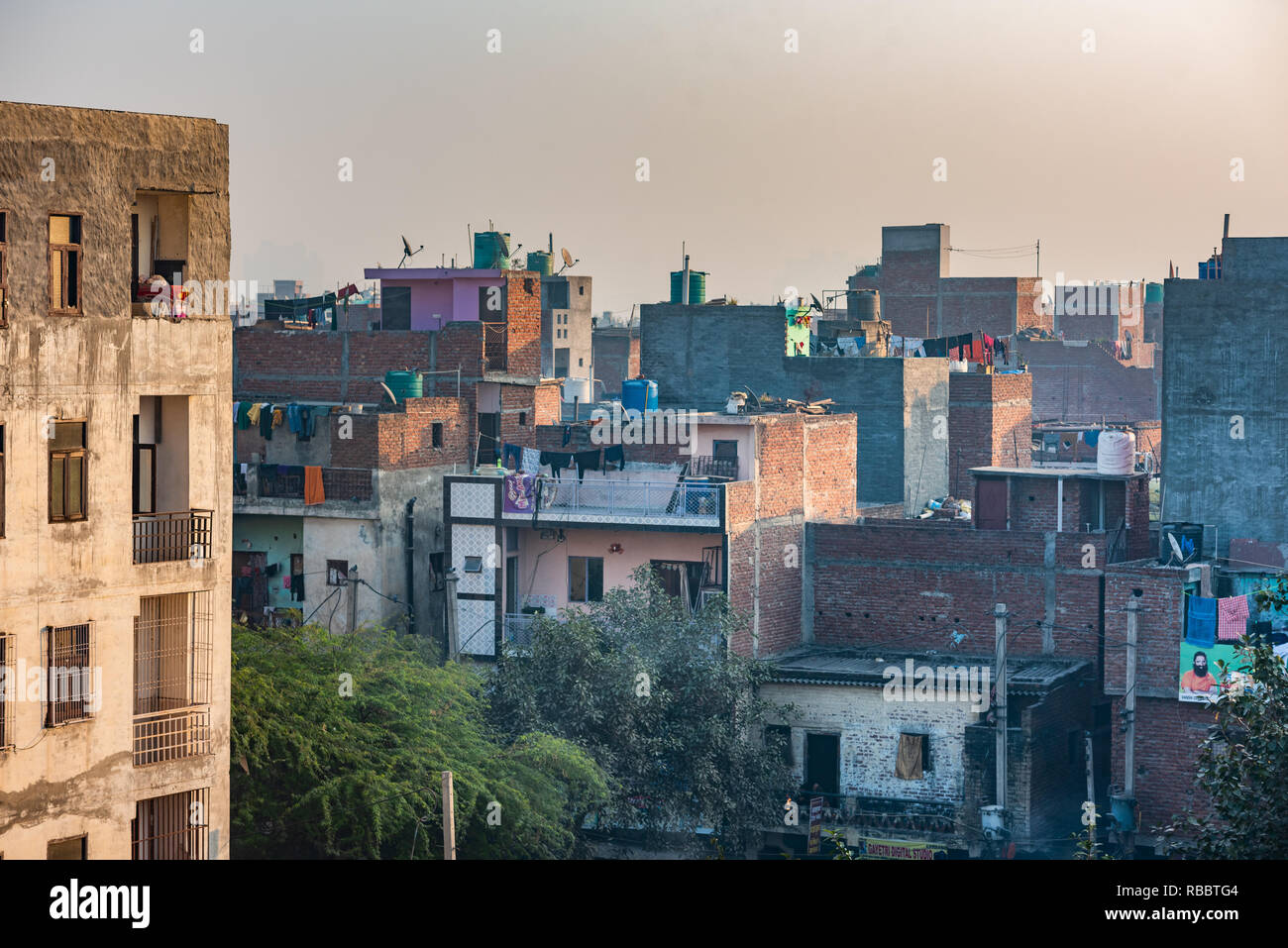 Buildings and roofs in the resettlement New Delhi locality of JJ Colony Madanpur Khadar provide an interesting urban landscape in the morning light Stock Photo