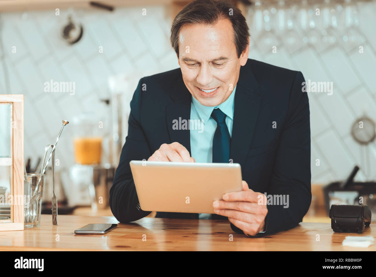 Making research. Handsome man in black suite holding tablet searching information in internet Stock Photo