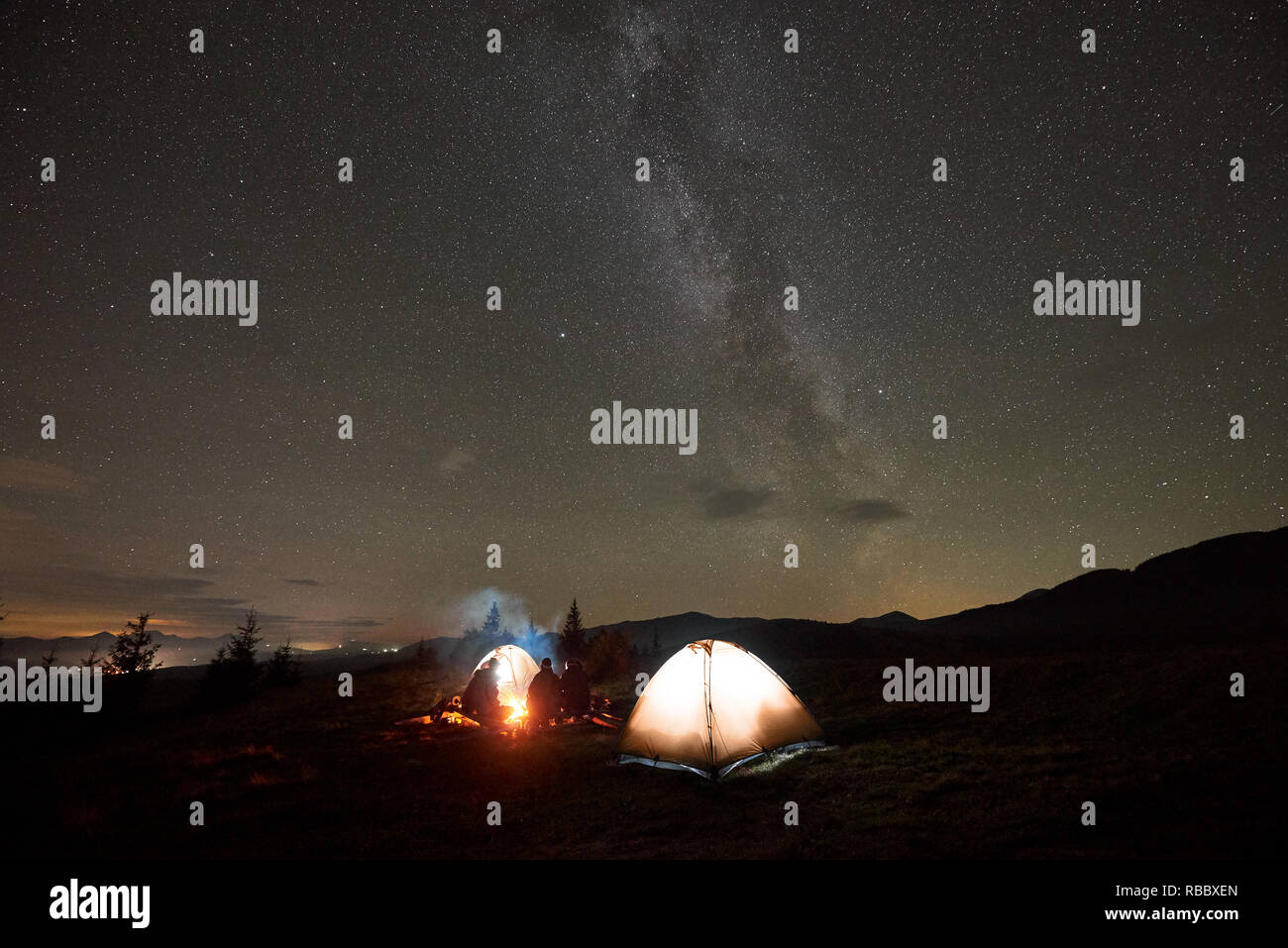 Night Camping Under Beautiful Starry Sky Group Of Four People Men And Woman Resting By Burning Campfire At Tourist Tents Under Dark Sky With Bright Stock Photo Alamy