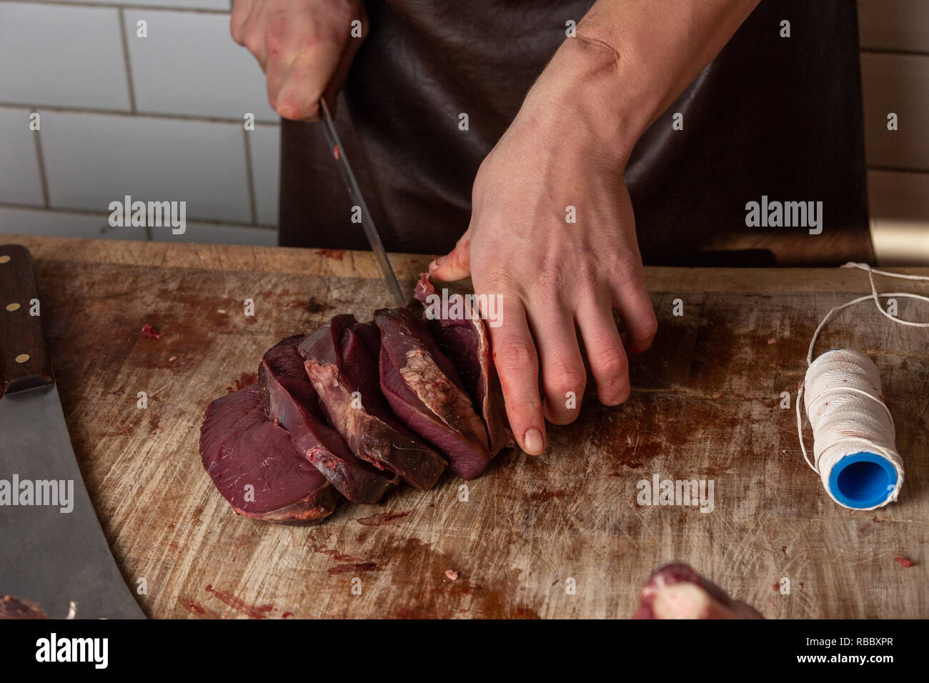 Butcher preparing venison meat at the Gog Farm Shop, Stapleford, Cambridge, Cambridgeshire Stock Photo