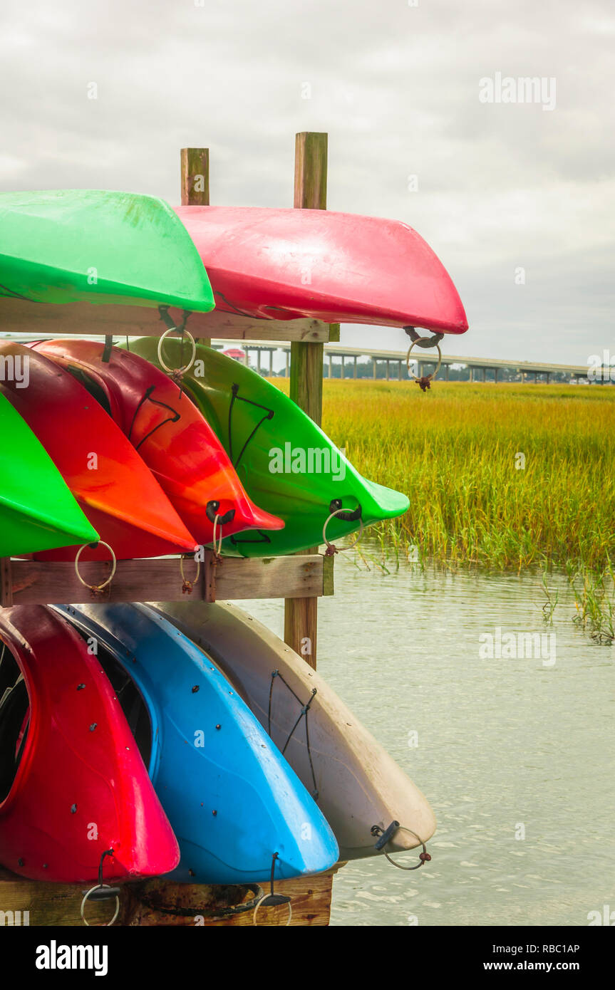 Kayaks in many colors are stacked and tied up on Hilton Head Island dock on water Stock Photo