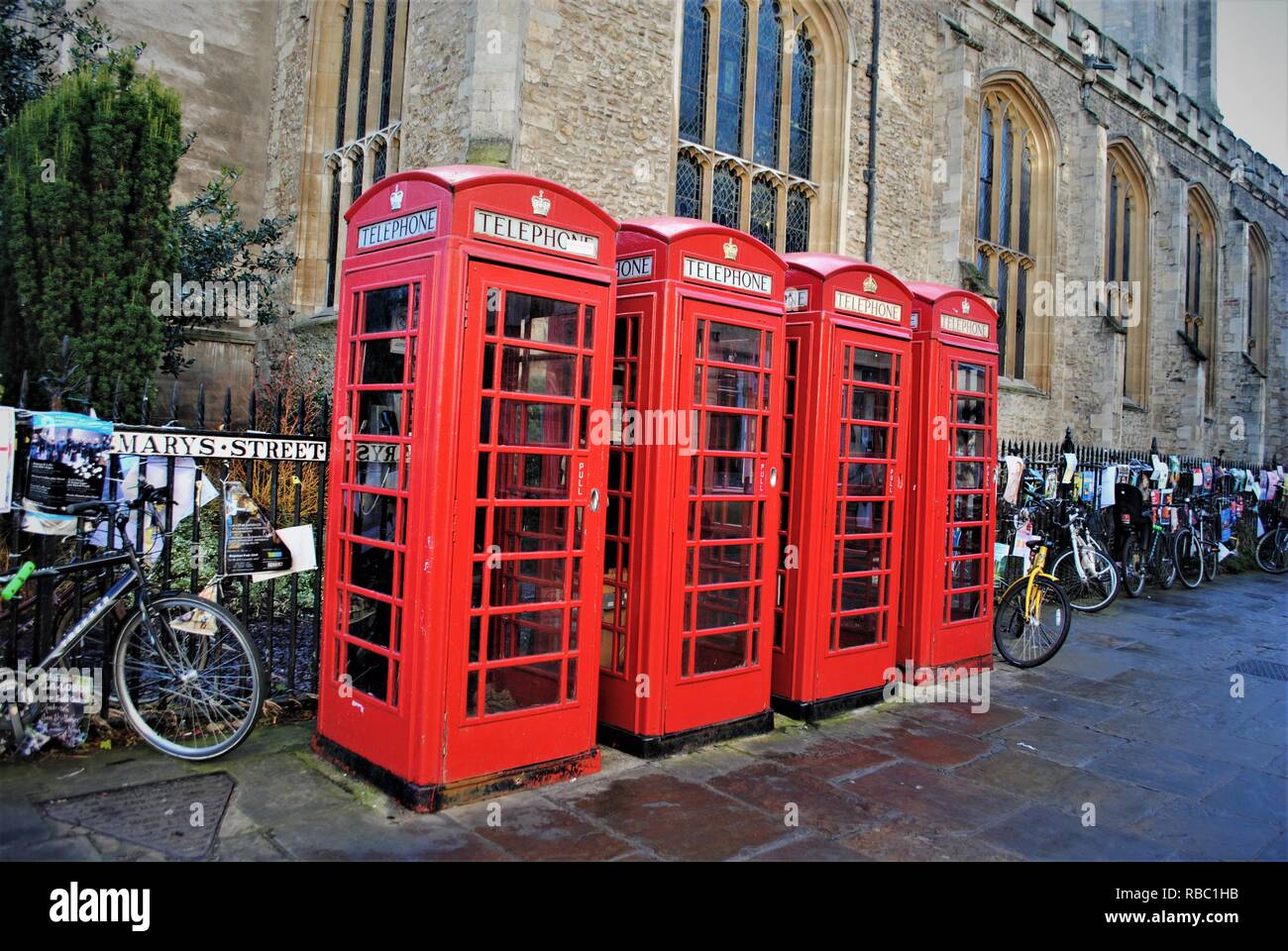 4 British red telephone e boxes outside a church in Cambridge city centre Stock Photo