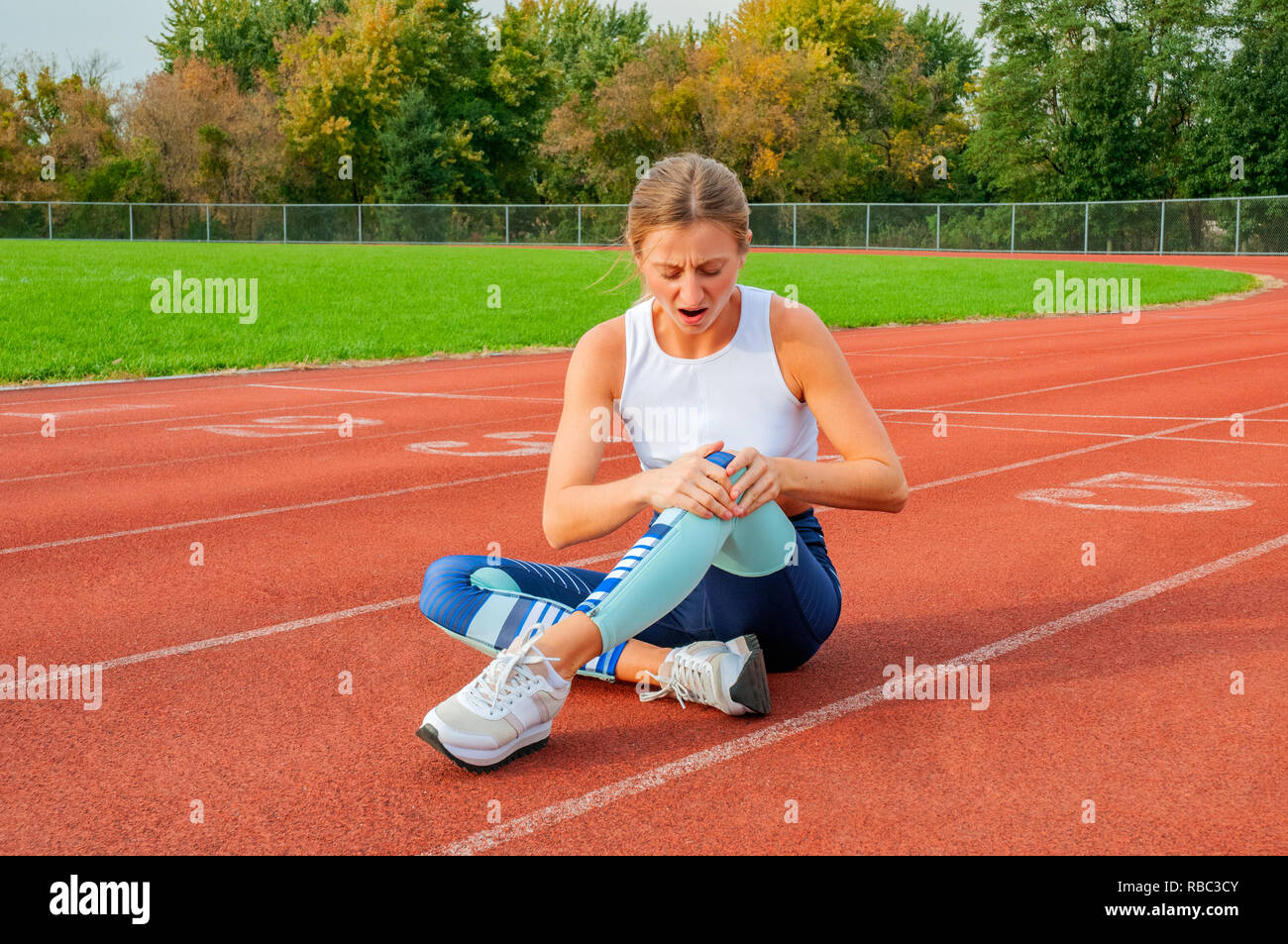 Sport knee injury. Woman has pain in knee after run outdoors at stadium