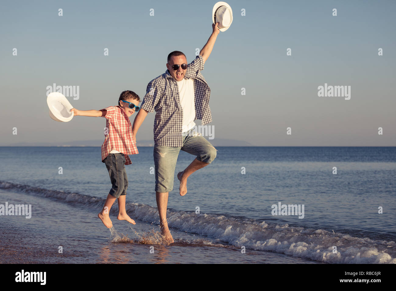 Father and son playing on the beach at the day time. People having fun outdoors.  Concept of happy vacation and friendly family. Stock Photo