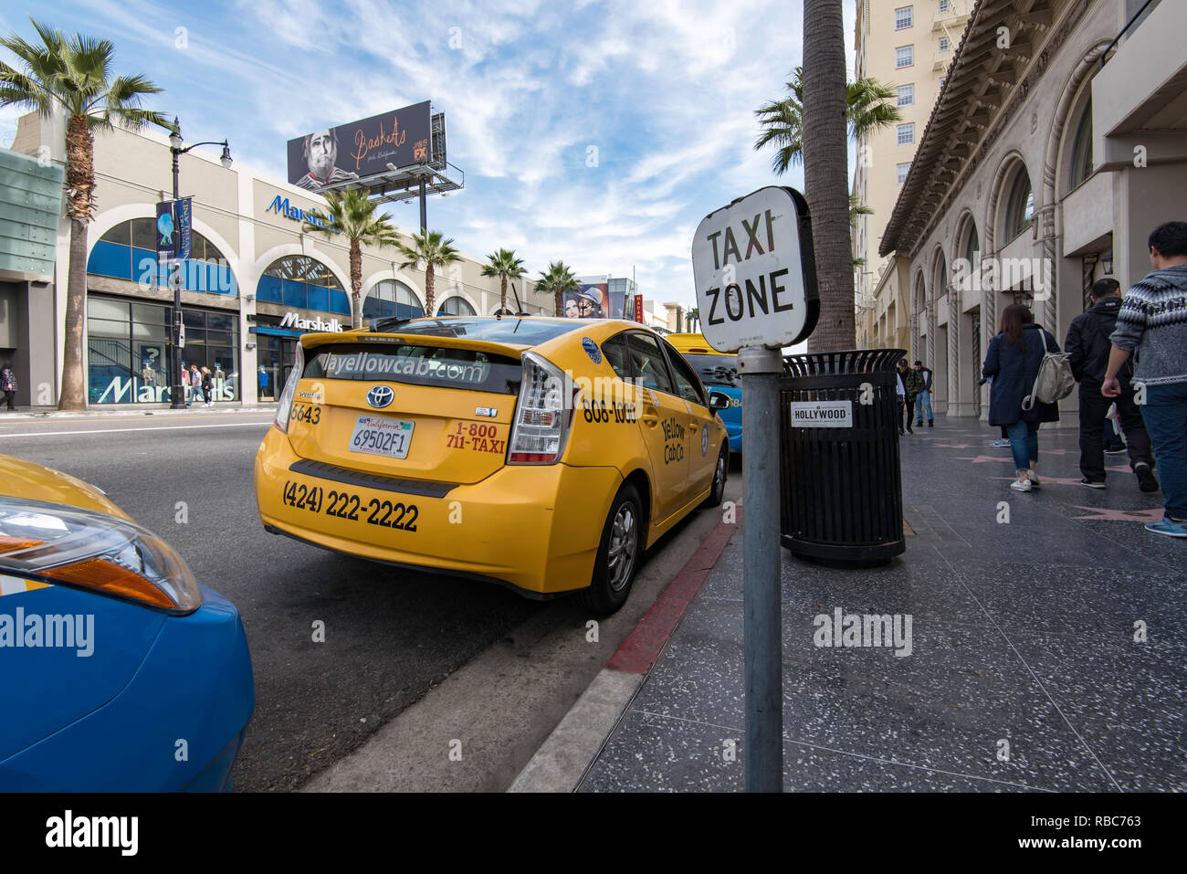 People walking down Hollywood Boulevard past a yellow Toyota Prius taxi cab in a taxi zone in Los Angeles, California, USA Stock Photo