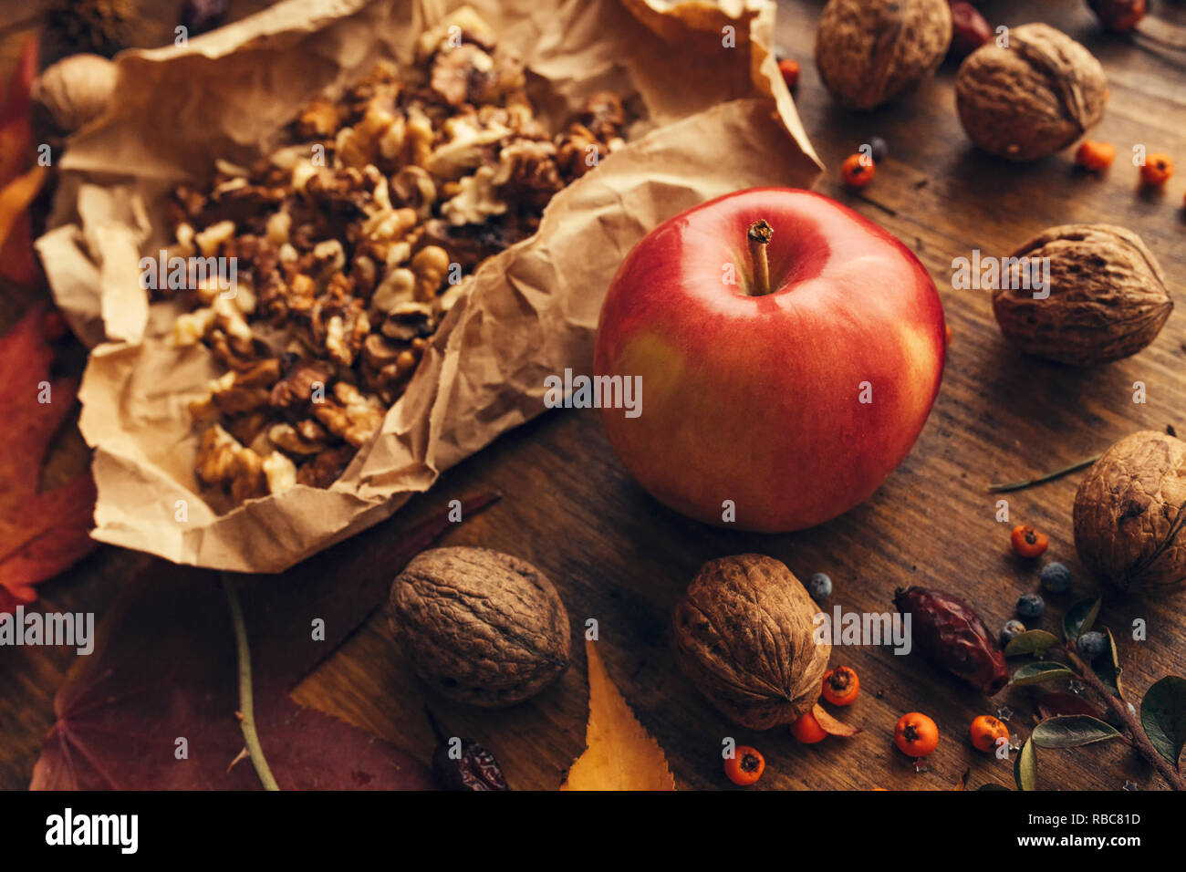 Apple and walnut, autumn abundance - healthy organic fruit on wooden table decorated with colorful maple leaves and berries, close up Stock Photo