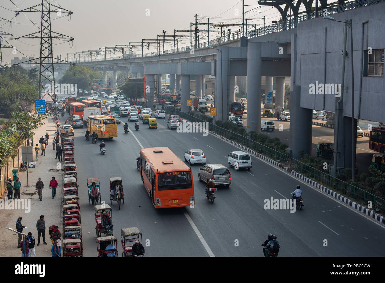 View of the travel interchange outside Sarita Vihar Metro station in New Delhi with rickshaws waiting for customers, buses and traffic moving. Stock Photo