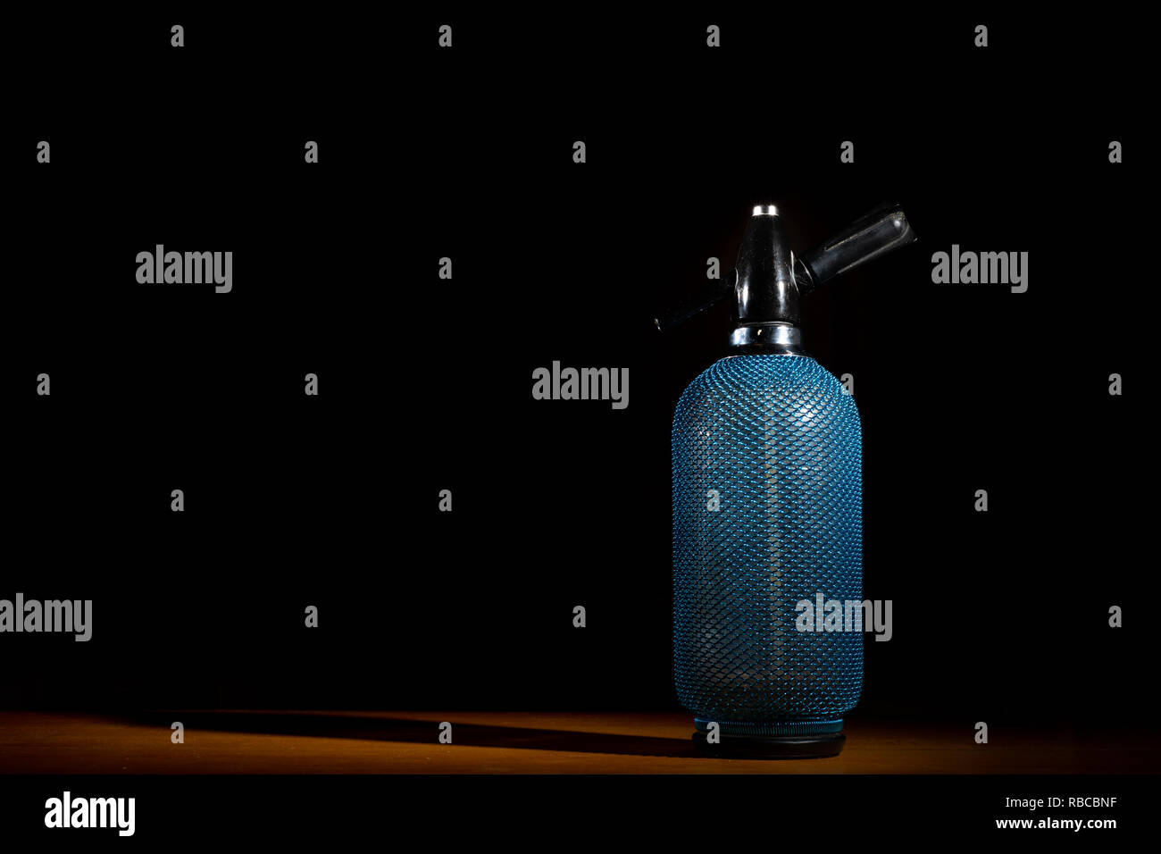 Closeup of a blue soda bottle standing on a table, black background Stock Photo