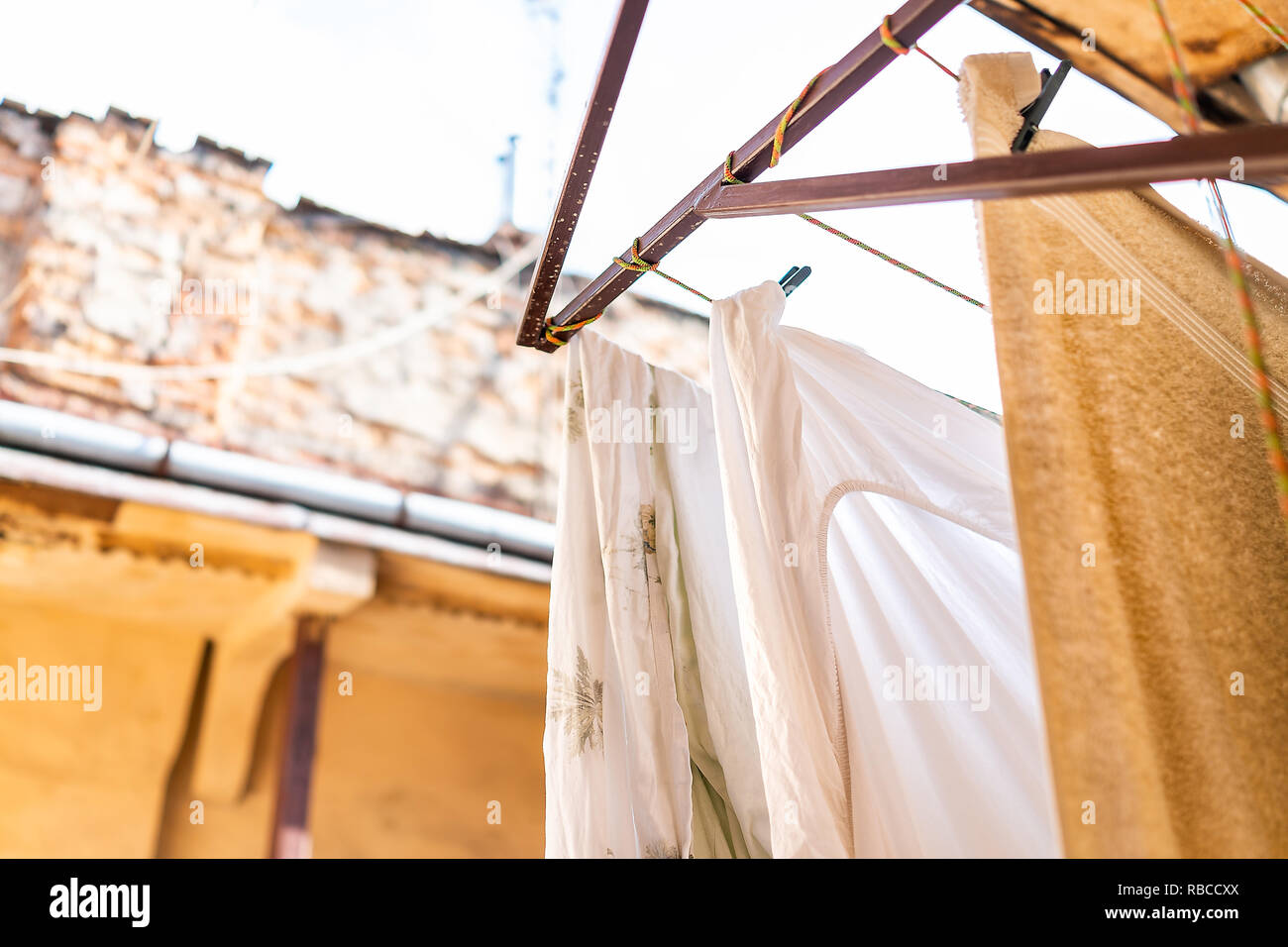 Closeup of yellow hanging clothes in summer with bedding linen and towels drying on rack clothesline line in Ukraine by old vintage Lviv Ukrainian apa Stock Photo