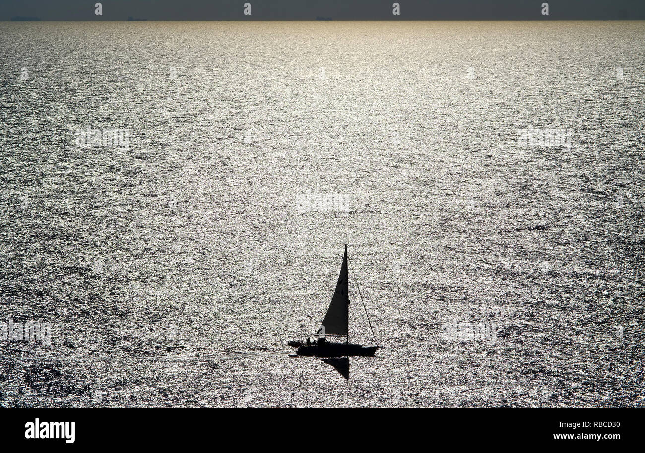 Small sailing boat on shining sea. Stock Photo