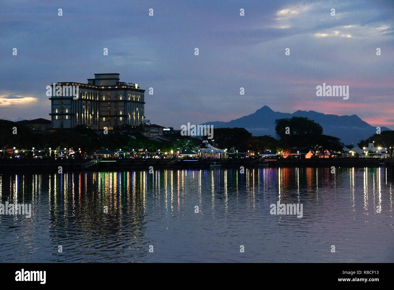 Buildings along Sungai Sarawak (Sarawak River) and Mount Santubong at sunset, Kuching, Sarawak (Borneo), Malaysia Stock Photo