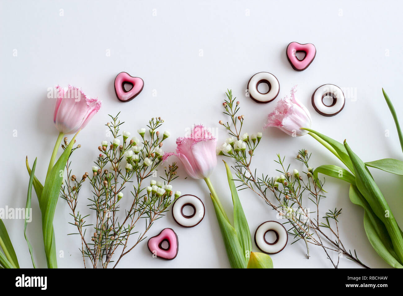 Spring floral flat lay with pink tulips and heart shaped sweets Stock Photo