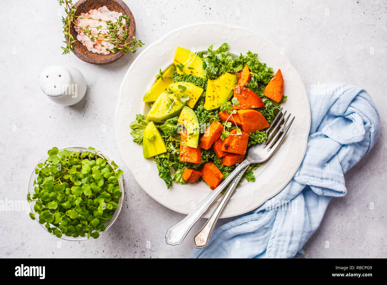 Healthy green kale salad with avocado and baked sweet potatoes. Plant based diet concept, detox food. Top view, white background. Stock Photo