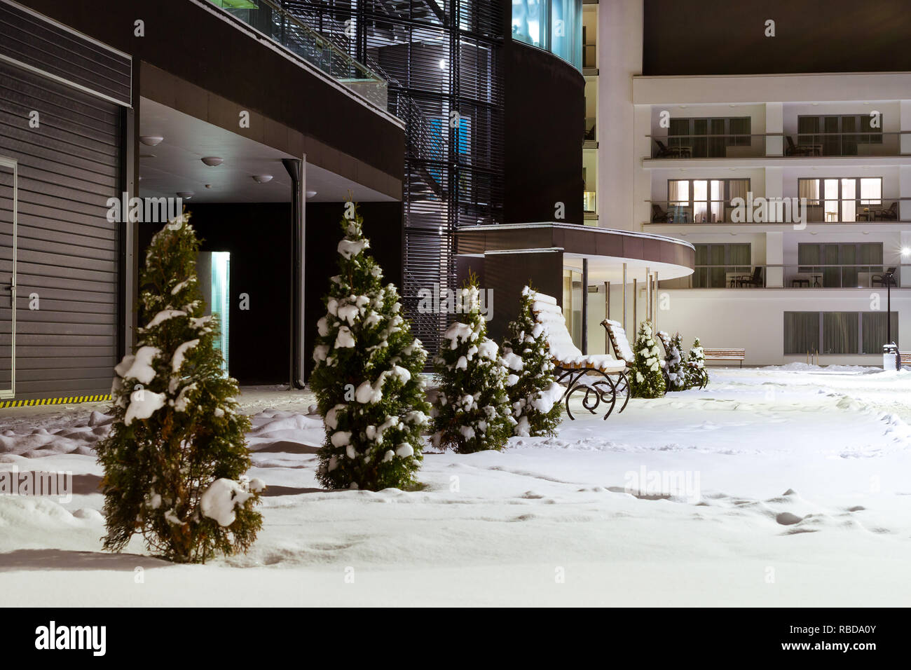 Modern building made of glass and concrete amidst snowy winter landscape at night. Severe Northern winter and snowy weather. Snow-covered wooden benches. Narva-Joesuu Stock Photo