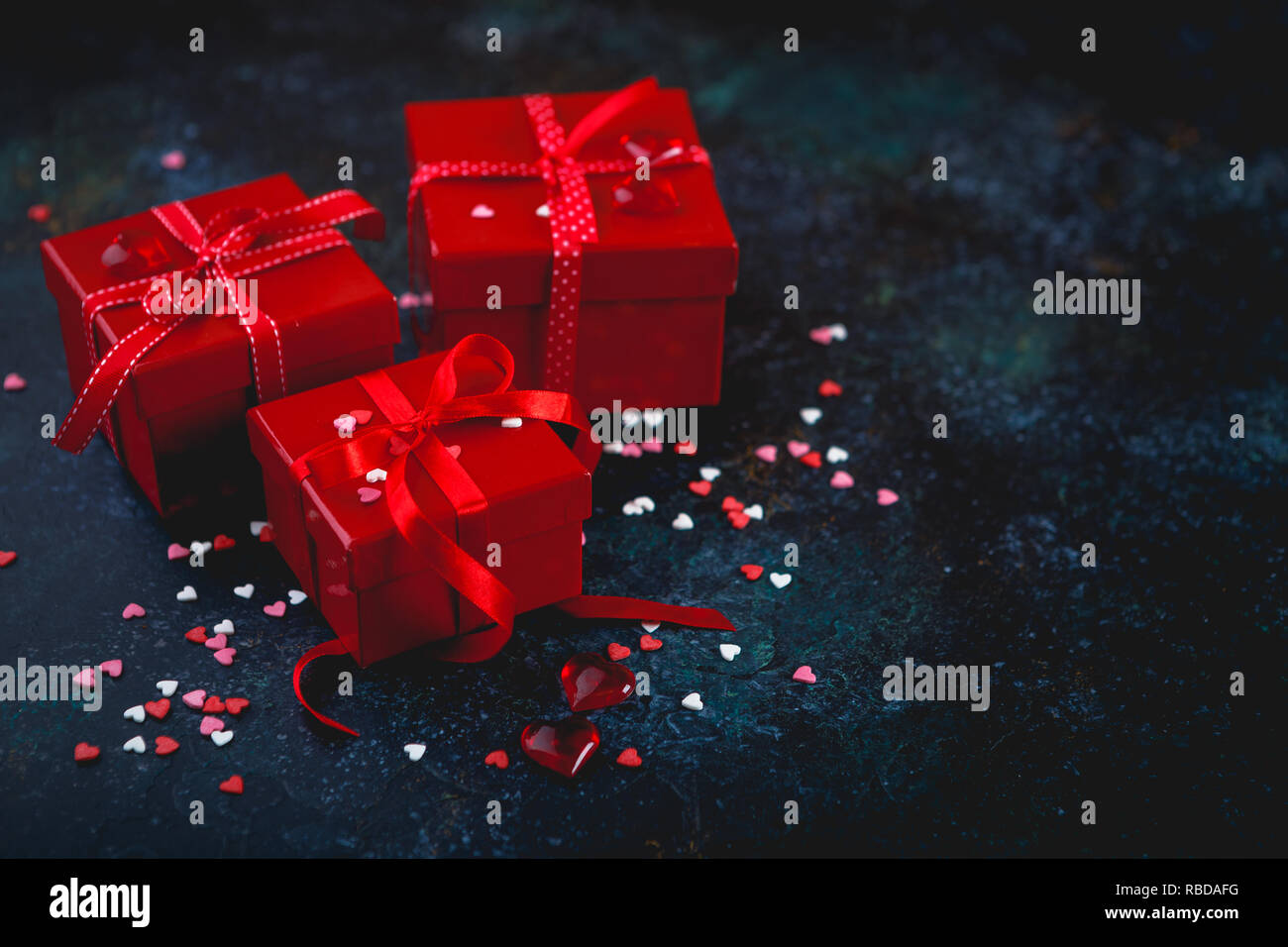 Gift red boxes with red bow ribbons and hearts on dark background for ...