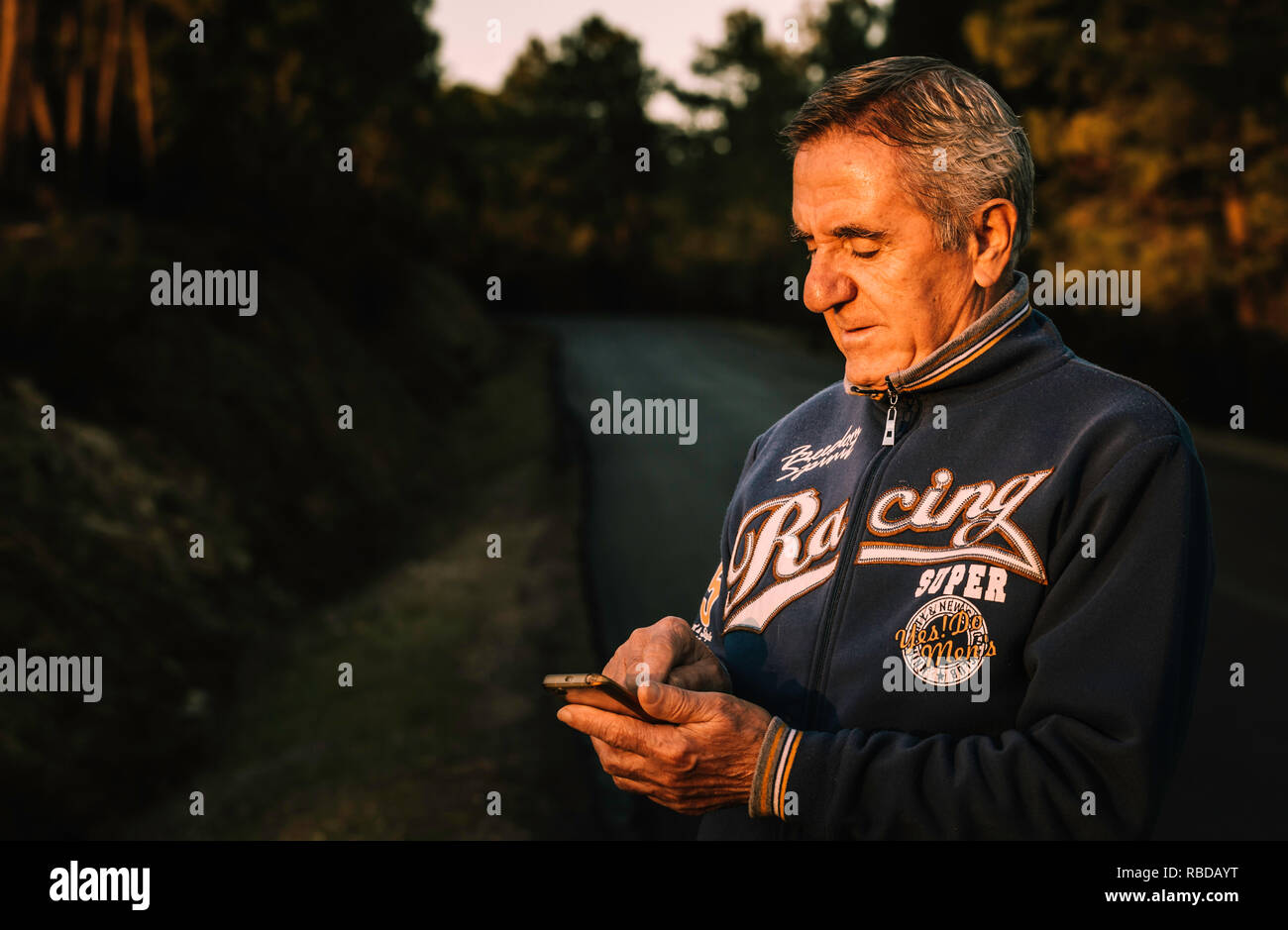 Handsome senior man using smartphone on the side of the road Stock Photo