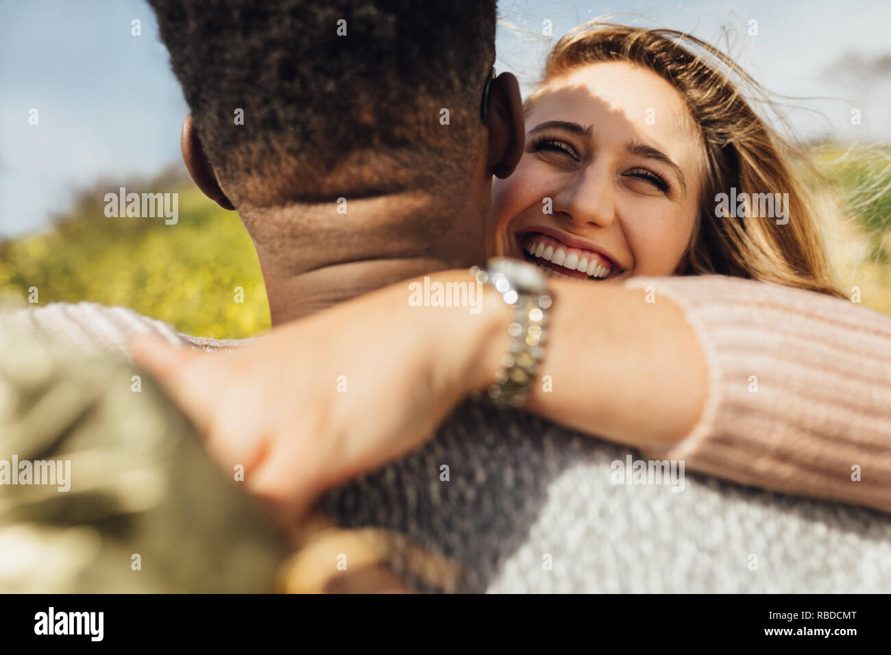 Couple in love standing outdoors. Woman putting her arms around her boyfriend and laughing. Stock Photo
