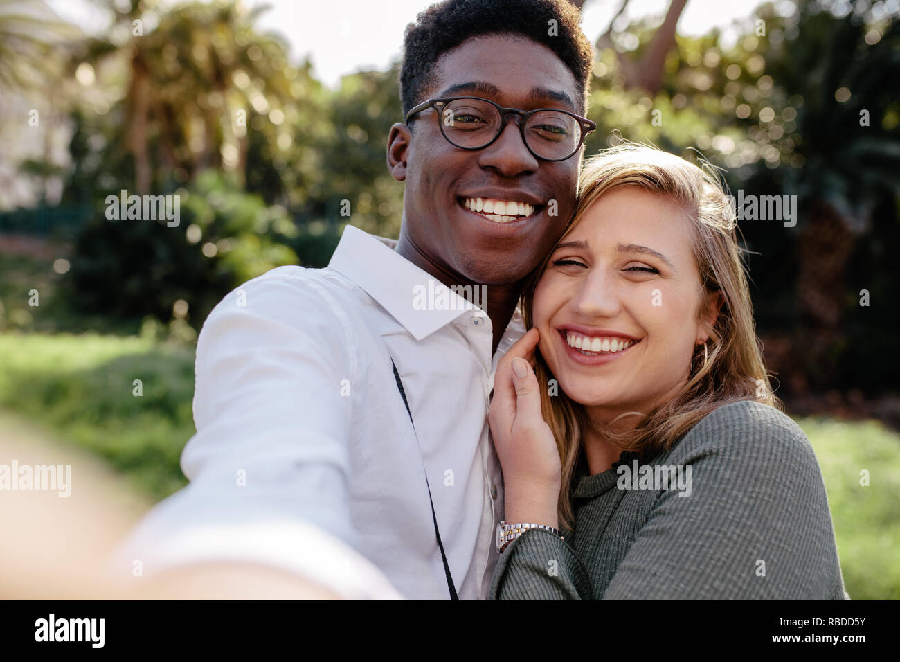 Beautiful interracial couple making a selfie outdoors. African man with caucasian woman taking a self portrait. Stock Photo