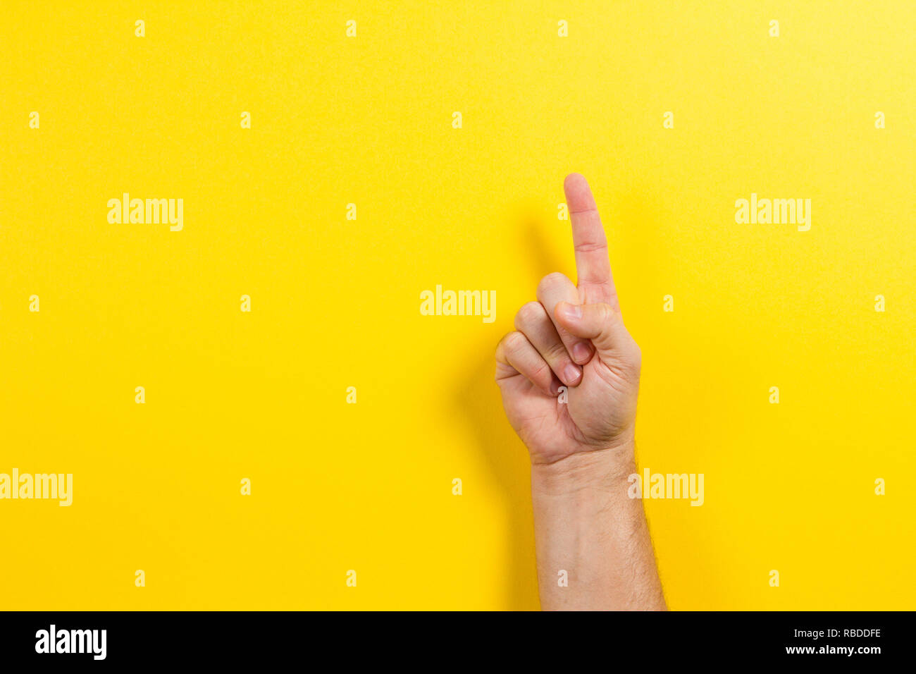 Man hand showing one finger on yellow background Stock Photo