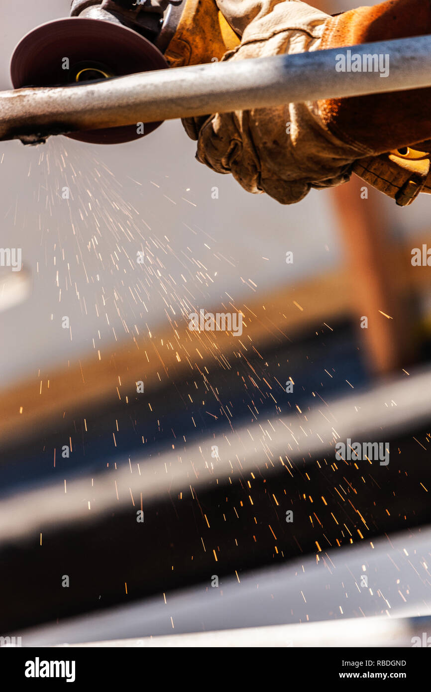 Welder At Shipyard Using Rotary Grinder On Metal Pipe Stock Photo