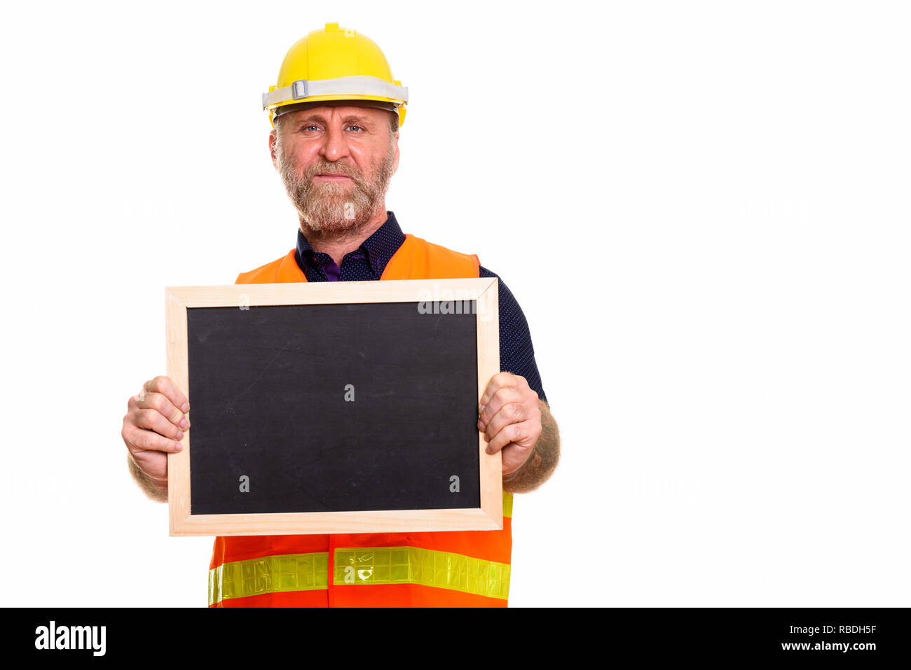 Mature bearded man construction worker holding empty blackboard Stock Photo