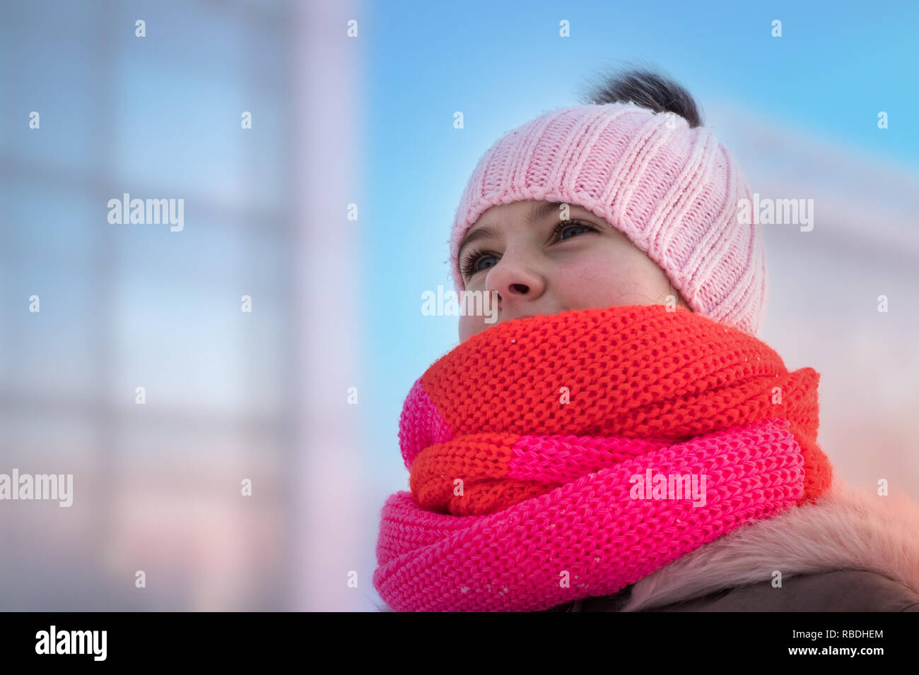girl in a knitted hat with a bub and a fluffy hood looks ahead Stock Photo