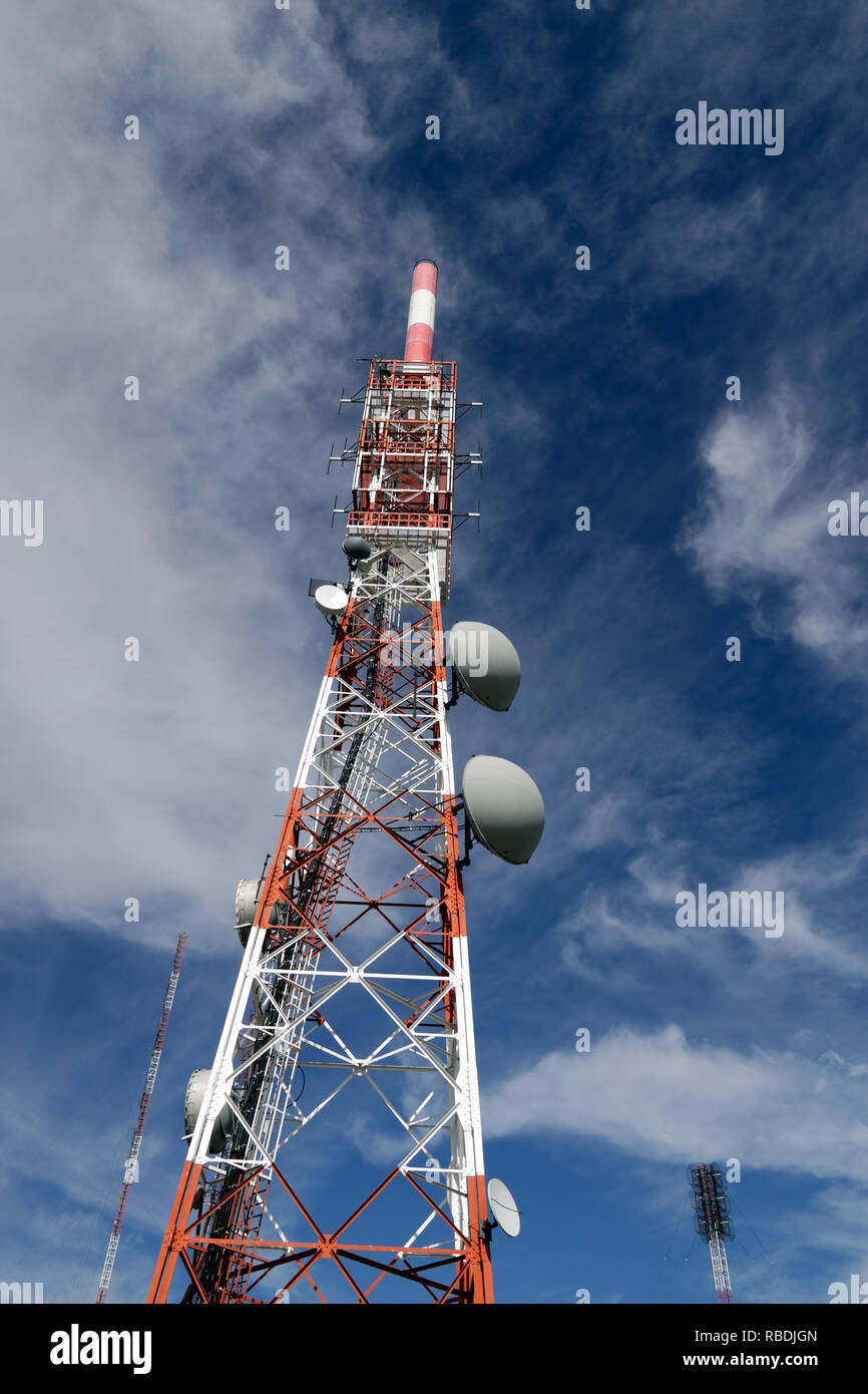 Interesting perspective of a multiple broadcast station against mountain deep blue sky with white clouds Stock Photo