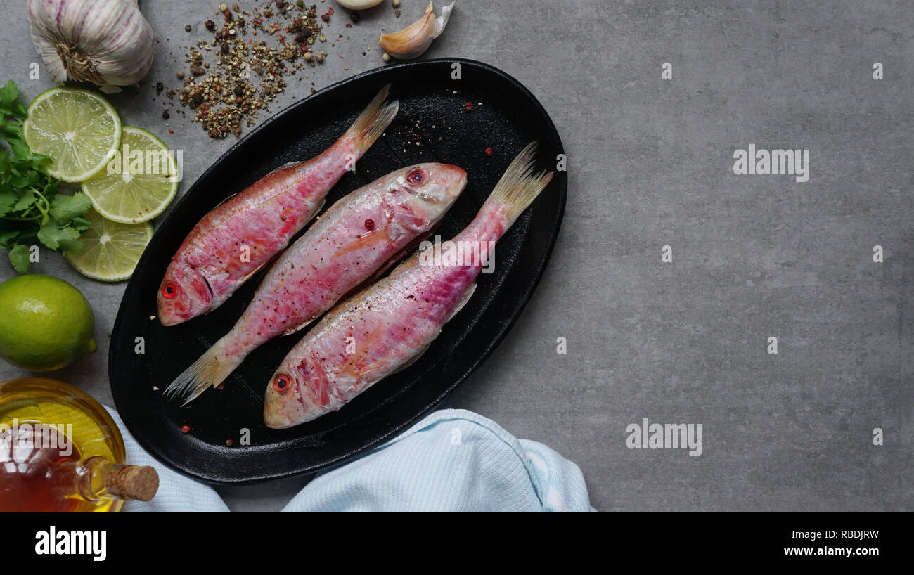 Fresh fish red mullet with lime and seasonings on an cutting board Top view Stock Photo