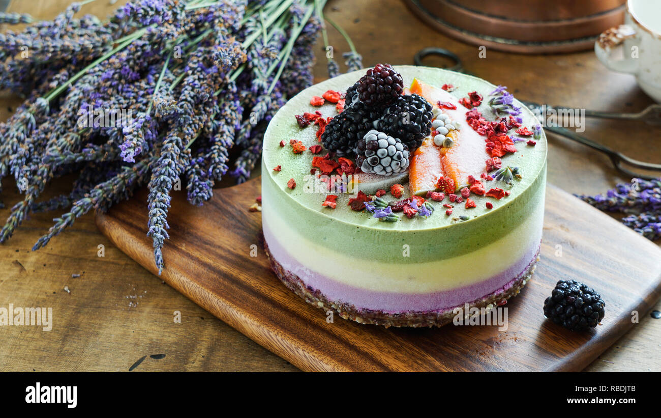 Vegan raw cheesecake with blueberry, cherry, matcha tea, orange,  cashew cream, coconut butter and coconut milk, and base made of almonds, dates  and  dried apricots, oat flakes, lyophilisated berry Stock Photo
