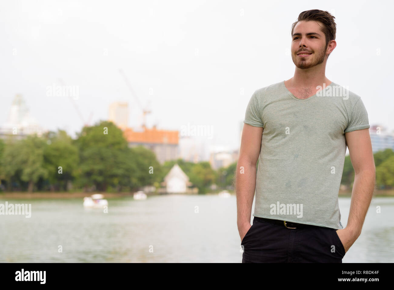 Portrait of young handsome man relaxing and smiling in park Stock Photo