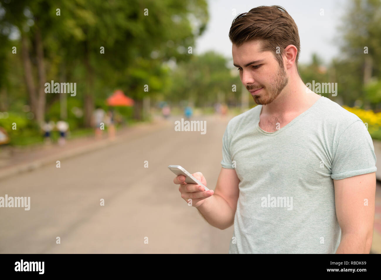 Portrait of young handsome man using mobile phone in park Stock Photo