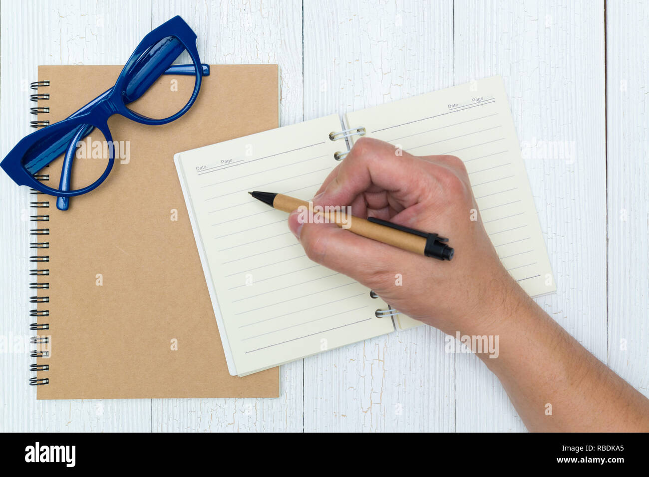 Man hand writing on blank page of notebook paper with pen on the wood ...